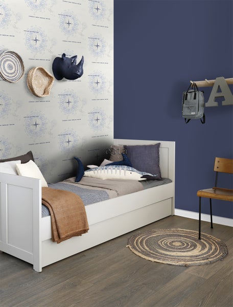 Kinderzimmer mit weißem Bett, Wanddekorationen und rundem Teppich