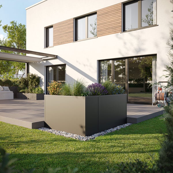 Modernes Hochbeet aus Metall in Anthrazit auf einer Holzterrasse vor einem Wohnhaus, bepflanzt mit Gräsern und Blumen.
