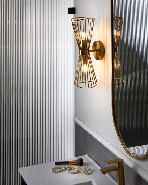 Badezimmer mit Waschbecken, Armatur, Spiegel und goldener Wandleuchte
