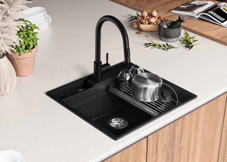 Schwarzes Spülbecken mit Abtropfgestell und Wasserhahn auf einer Küchentheke.