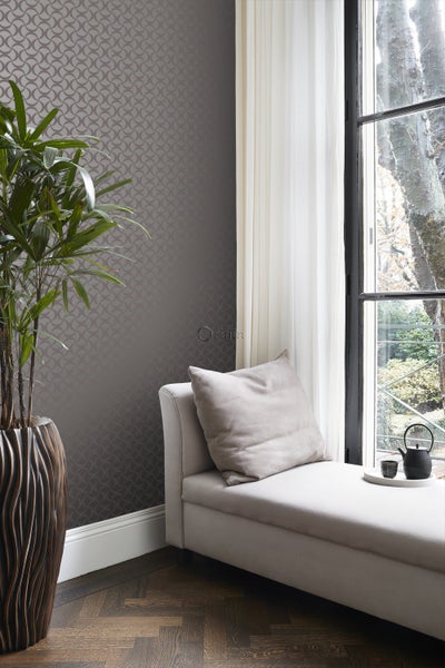 Zimmer mit gemusterter Tapete, Liege und Topfpflanze.