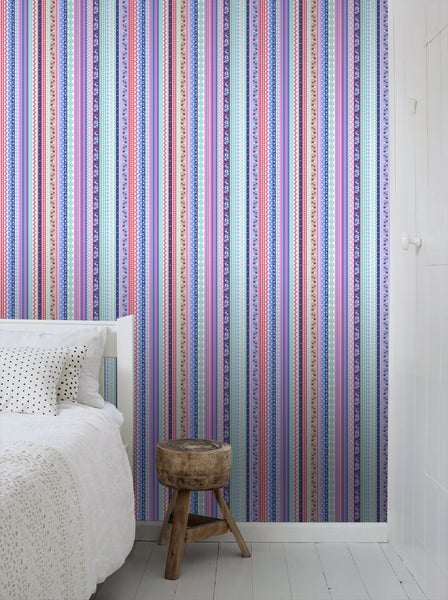 Schlafzimmer mit gestreifter Tapete und Holzhocker.