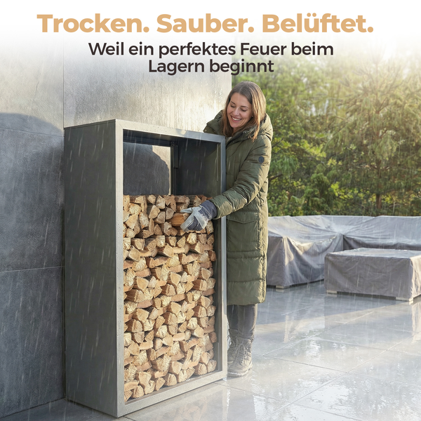 Eine Frau stapelt Brennholz in ein Kaminholzregal aus Metall im Freien auf einer Terrasse bei Regen.