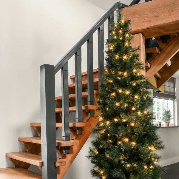 Dekorierter Weihnachtsbaum neben einer Holztreppe im Innenbereich