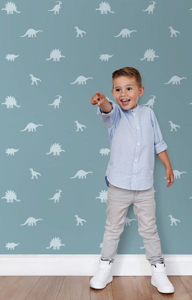 Junge, der auf eine Wand mit Dinosaurier-Tapete zeigt