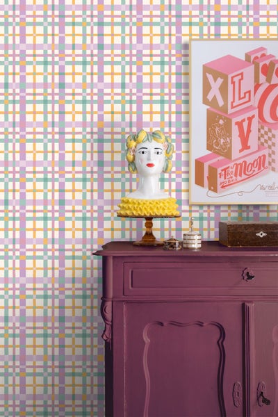 Vliestapete mit farbigem Karomuster in einem Wohnraum mit violetter Kommode und Dekoration im Vintage-Stil.