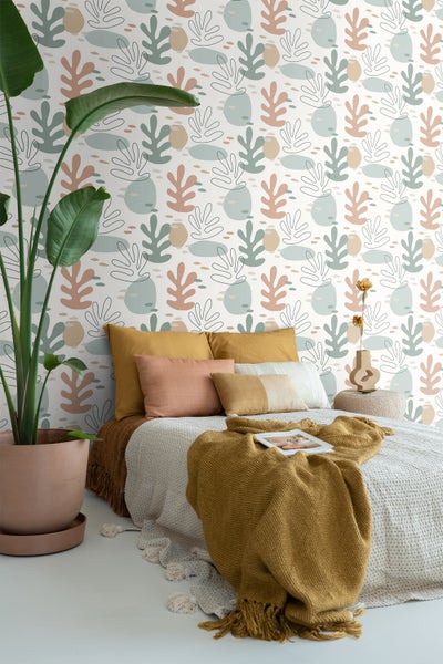 Schlafzimmer mit Bett, Kissen, Tagesdecke und einer gemusterten Tapete