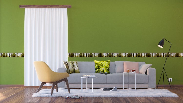Wohnzimmer mit grüner Wand, Bordüre mit Waldmotiv, Sofa, Sessel und Dekoration