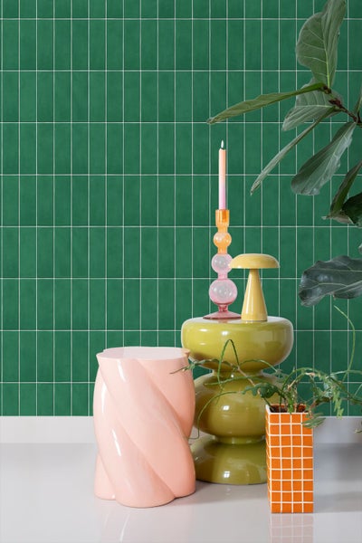 Wand mit grünen rechteckigen Fliesen in einem Raum mit dekorativen Wohnaccessoires und Zimmerpflanze