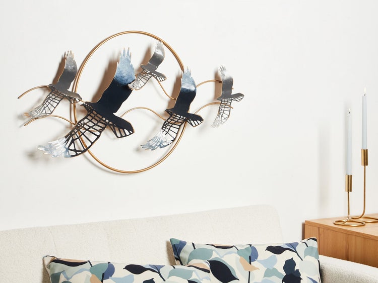 Wanddekoration aus Metall mit Vogelmotiv und kreisförmigem Rahmen über einem Sofa