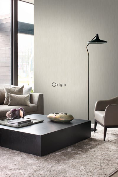 Wohnzimmer mit Couch, Sessel, Stehlampe, Tisch und Origin Logo an der Wand