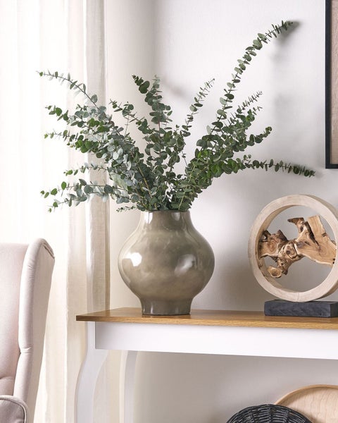 Dekoratives Arrangement mit Vase und Eukalyptus auf einem Tisch