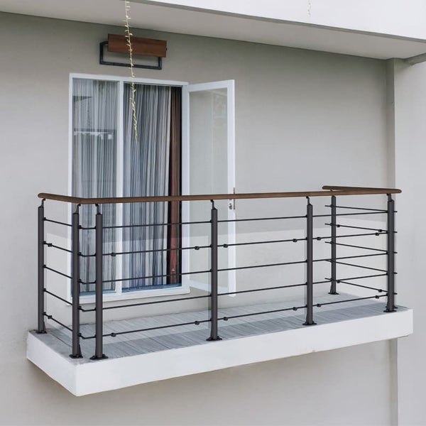 Balkon mit Metallgeländer und Holzbalken vor einer geöffneten Tür