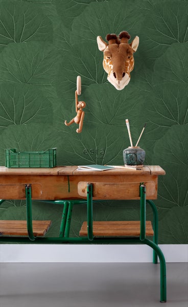 Zimmer mit grüner Blättertapete, einer alten Schulbank, einer Giraffen-Wanddekoration und einer Affenfigur.