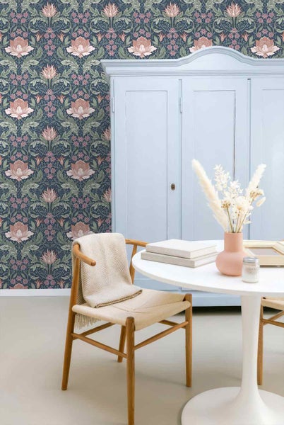 Wohnraum mit floral gemusterter Tapete an der Wand, einem hellblauen Schrank, einem Holzstuhl und einem runden weißen Tisch mit Dekoration.