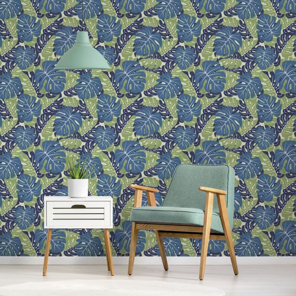 Dekoratives Zimmer mit Monstera-Blättertapete, Sessel und Beistelltisch.