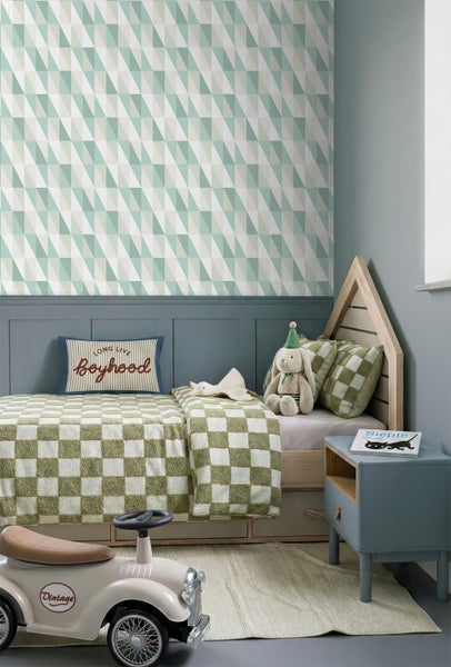 Modernes Kinderzimmer mit geometrisch gemusterter Tapete in Grün und Weiß, einem Hausbett und strukturierter Einrichtung.