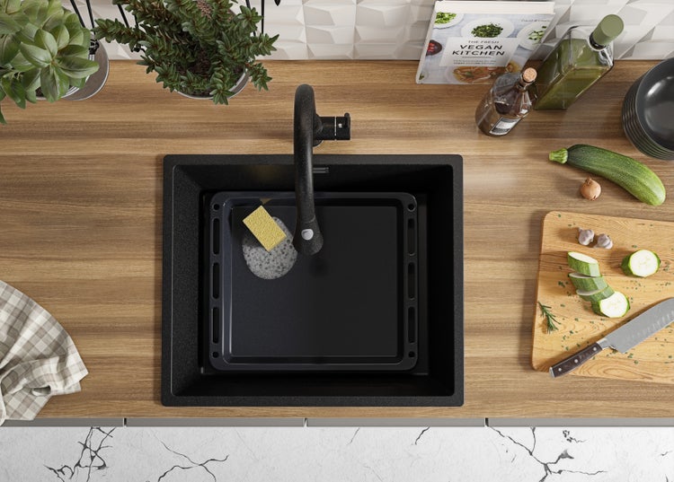 Draufsicht auf eine Spüle mit Armatur, Spülschüssel, Gemüse und Kochutensilien in einer Küche.