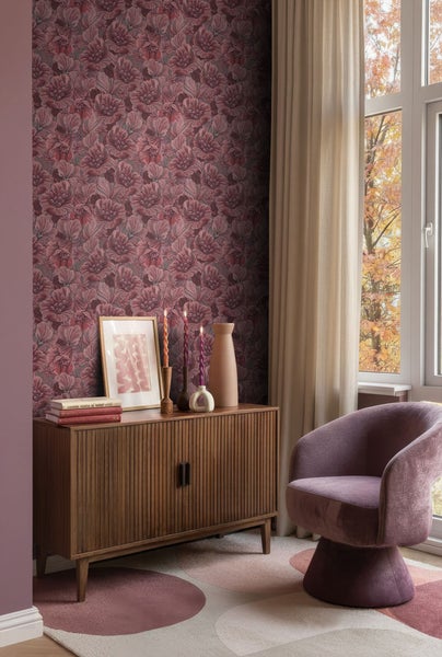 Wohnzimmer mit blumiger Tapete, Holzkommode, Sessel und Fenster