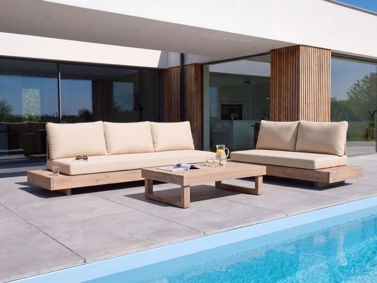 Moderne Loungegruppe aus Holz mit Polsterauflagen auf einer Terrasse am Pool vor einem Wohnhaus mit großen Fensterfronten.