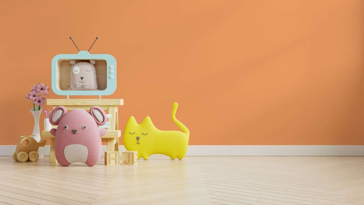 Kinderzimmer mit orangefarbener Wandfarbe, hellem Parkettboden in Fischgrätoptik, Holzmöbeln und bunten Stofftieren.