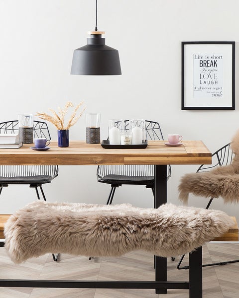 Modernes, helles Esszimmer mit Holztisch, Holzbank mit Kunstfell, Metallstühlen, Pendelleuchte und Tischdekoration.