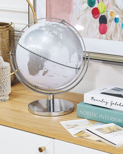 Dekorativer Globus mit silberfarbenen Details auf einem Schreibtisch