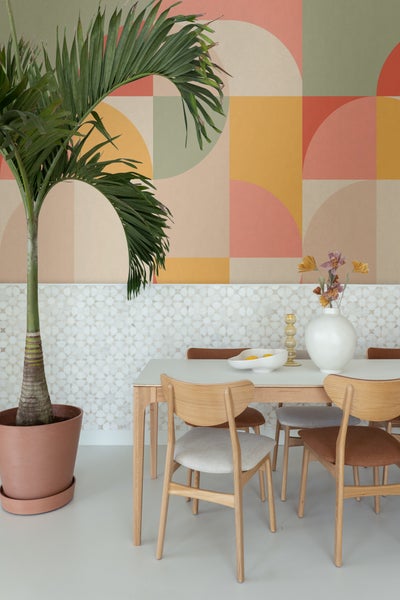 Esszimmer mit Esstisch, Stühlen und Topfpflanze vor gemusterter Wand