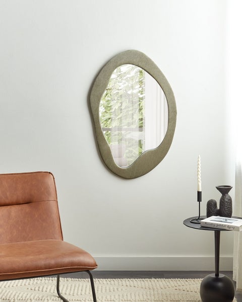 Wohnzimmer mit organisch geformtem Spiegel, Sessel und Beistelltisch.