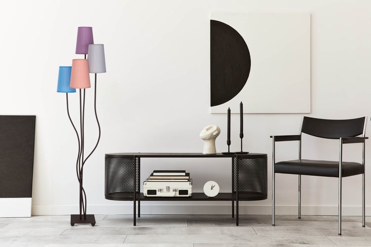 Wohnzimmer mit Stehlampe, Kommode, Dekoration und Stuhl.