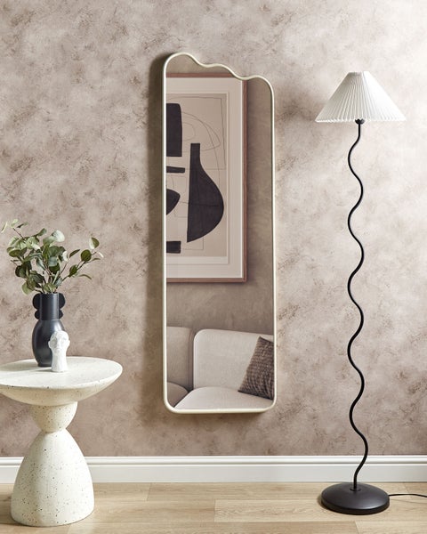 Dekoratives Interieur mit Stehlampe, Spiegel und Beistelltisch mit Dekoration