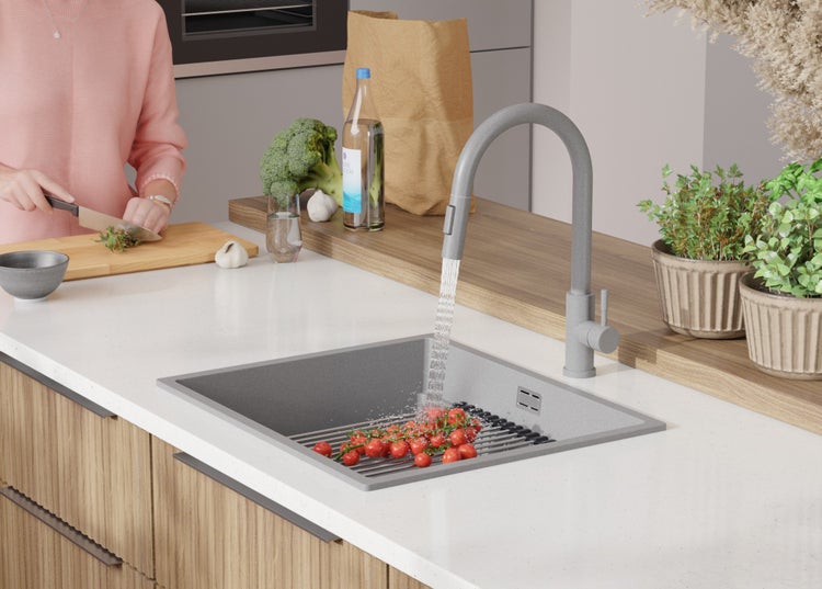 Küchenspüle mit Wasserhahn, Gemüsestand und Lebensmitteln auf der Arbeitsfläche.