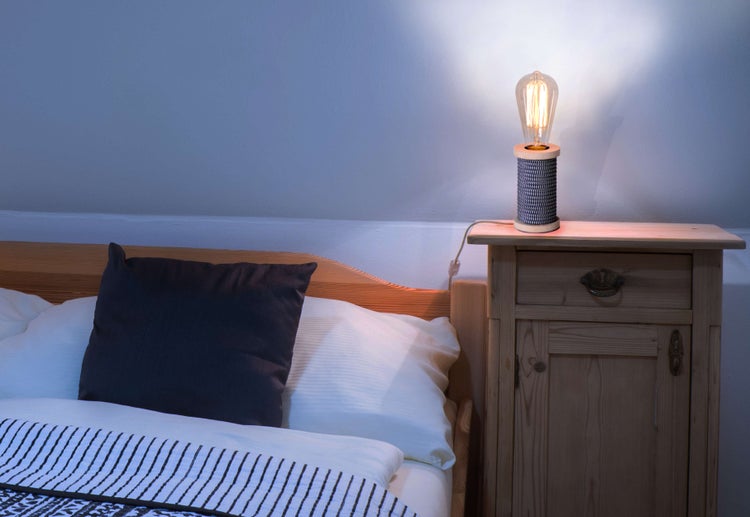 Schlafzimmer mit Bett, Nachttisch und dekorativer Lampe