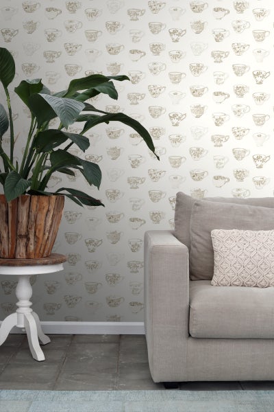 Raumansicht mit gemusterter Tapete, Pflanze im Holztopf auf Beistelltisch und Stoffsofa