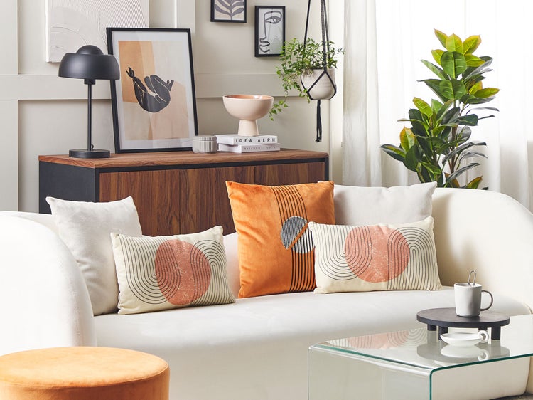 Wohnzimmer-Szene mit Sofa, Kissen, Tisch und Dekorationen für ein gemütliches Ambiente.