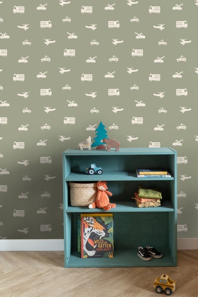 Kind auf Hocker vor Tapete mit Fahrzeugmuster