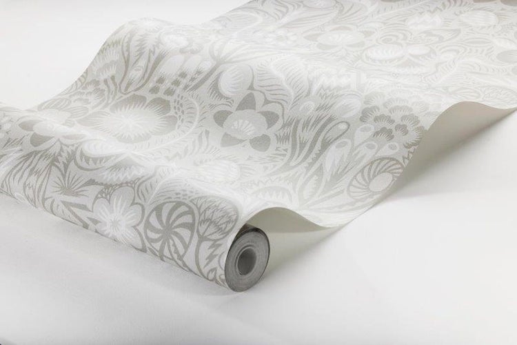 Dekoratives Schlafzimmer mit gemusterter Tapete, Rattankopfteil und Pflanzen