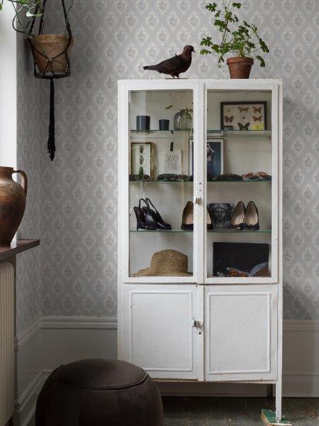 Dekoratives Wohnzimmer mit Tapete, Vitrinenschrank und Zimmerpflanzen