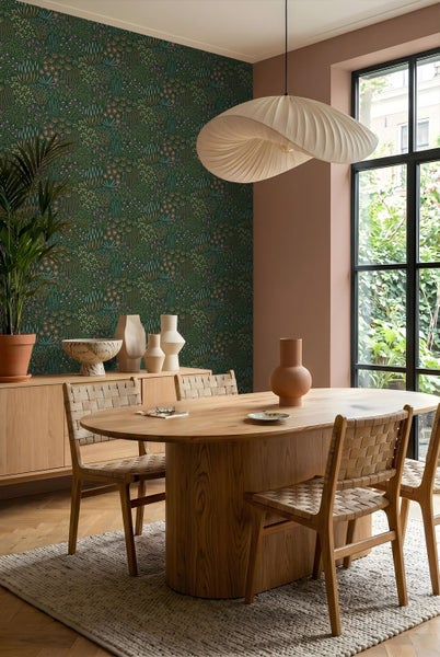 Kinderzimmer mit Blumentapete, rosa Wandpaneelen und Kleiderschrank aus Holz. Kleiderhaken mit Hut und Kleid sowie Stiefel auf Holzboden.