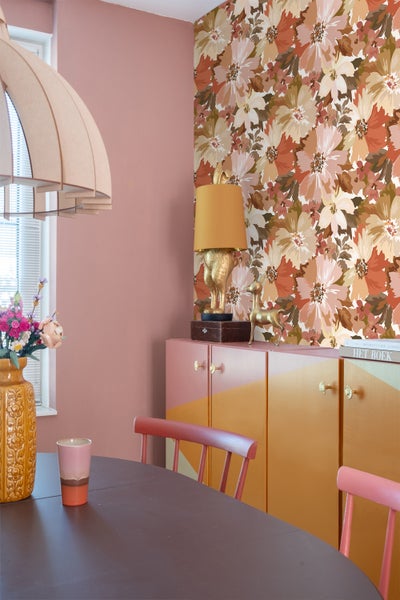 Esszimmer mit Esstisch, Stühlen, Schrank und floraler Tapete