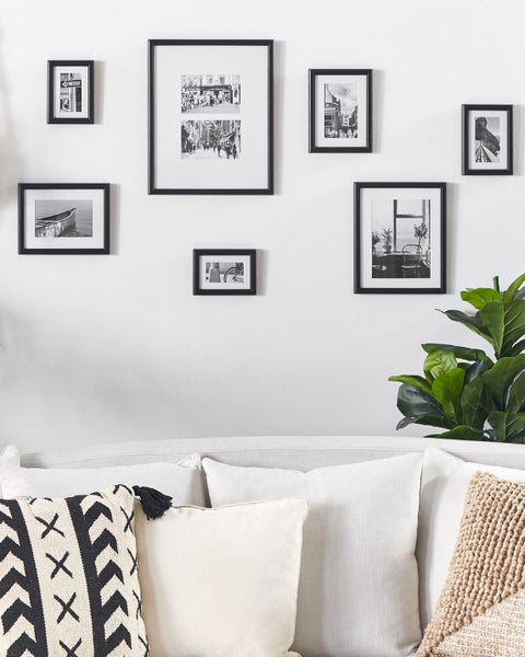 Wanddekoration mit mehreren rechteckigen Bilderrahmen und Sofakissen