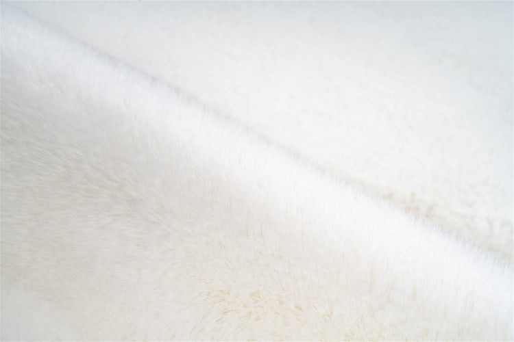 Detailansicht von weißem Kunstfell mit einer weichen und flauschigen Textur.