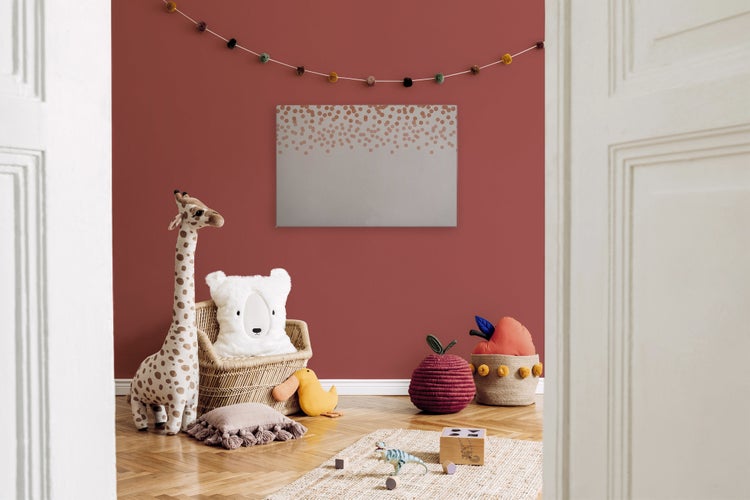 Ein Kinderzimmer mit Wandbild, Stofftieren wie Giraffe und Bär sowie einer Aufbewahrungskiste aus Rattan vor einer dekorierten Wand.