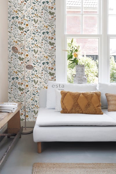 Heller Wohnraum mit floraler Tapete, weißem Sofa und Stehlampe.