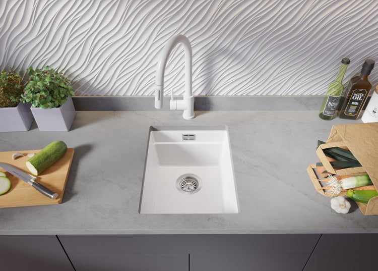 Spüle mit Armatur in einer modernen Küche mit Gemüse und Kräutern