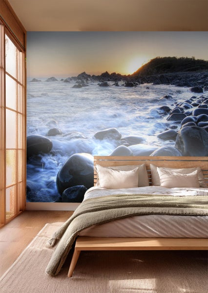 Schlafzimmer mit Fototapete einer felsigen Küste bei Sonnenaufgang