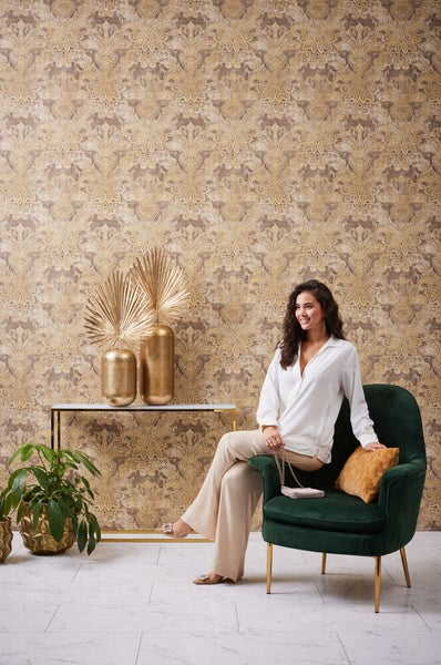 Frau mit Ohrring und Ringen vor einer gemusterten Tapete