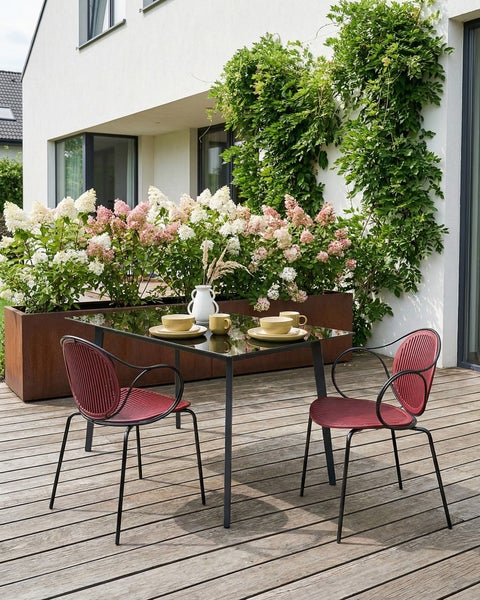 Terrasse mit Esstisch, Stühlen und Pflanzkübel