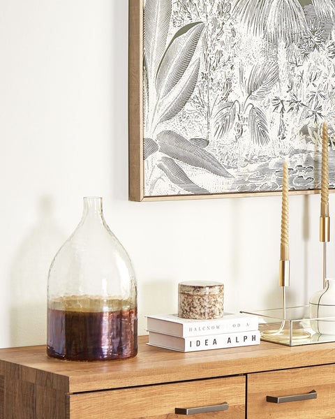 Dekoratives Arrangement auf einem Holzschrank mit Gemälde und verschiedenen Wohnaccessoires.