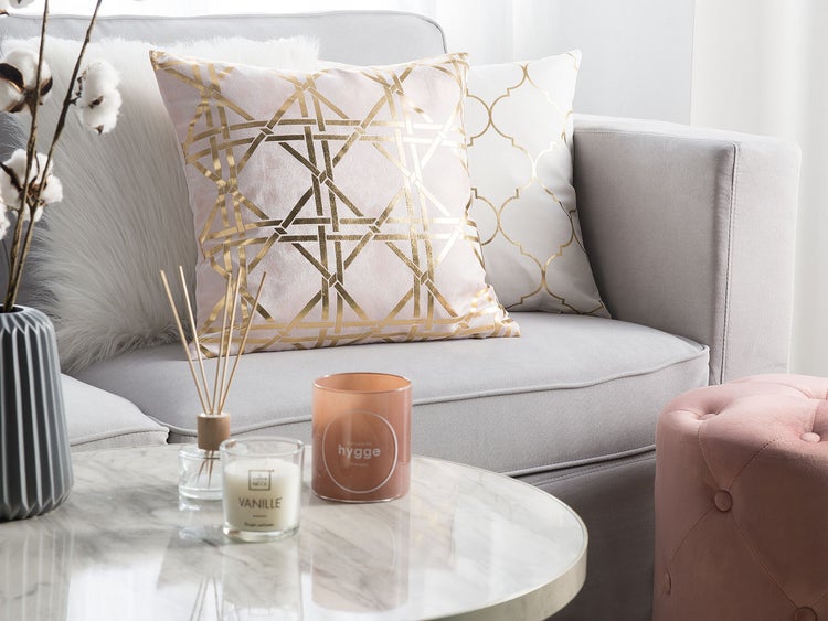 Dekorative Kissen auf einem Sofa mit Kerze und Duftstäbchen auf einem Tisch